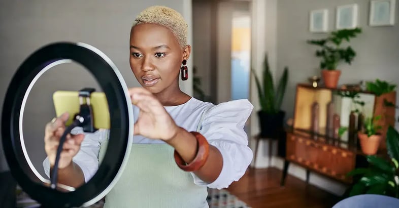 Woman-setting-up-home-filming-with-smartphone-ring-light-1200x628-GettyImages-1313649377